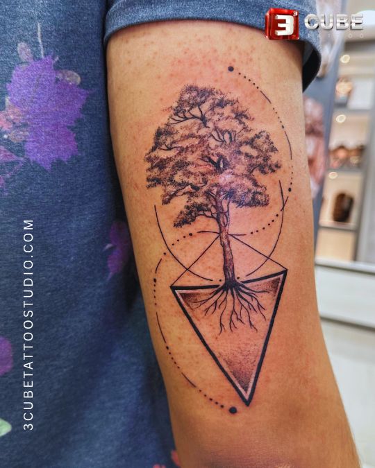 A nature-themed band tattoo featuring a detailed tree with roots and geometric patterns, representing growth, grounding, and connection to nature.