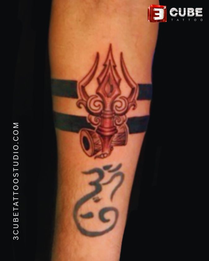 Trishul band design with Shiva symbolism inked on the forearm, created by 3 Cube Tattoo.